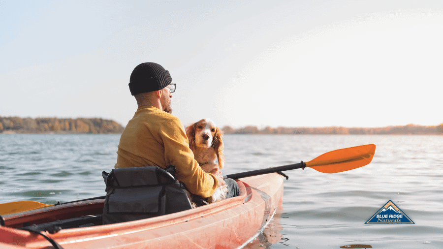 Man and his dog in a kayak on a lake.